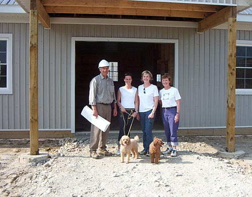 Gary van Bolderen standing with stable design drawings beside clients in front of their horse barn construction project